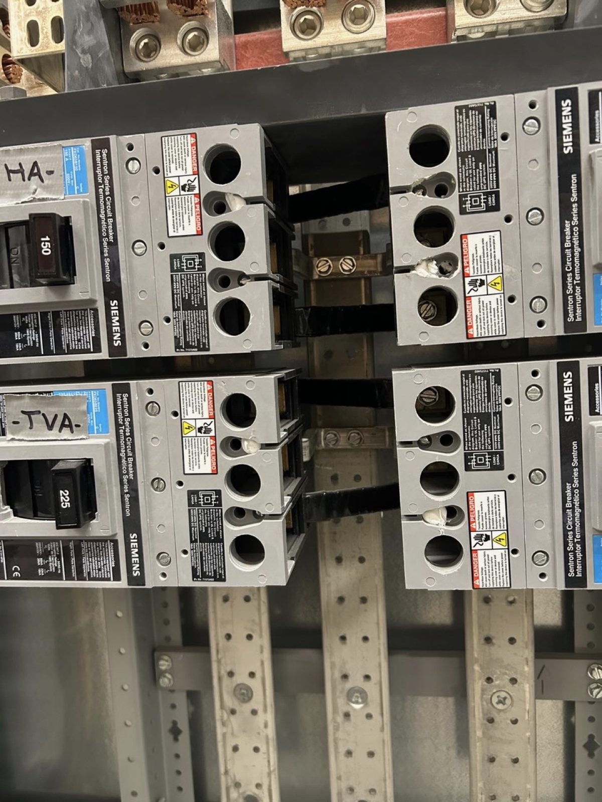 Siemens Sentron 150A and 225A circuit breakers racked in the panel, each with a hand-labeled tape tag.