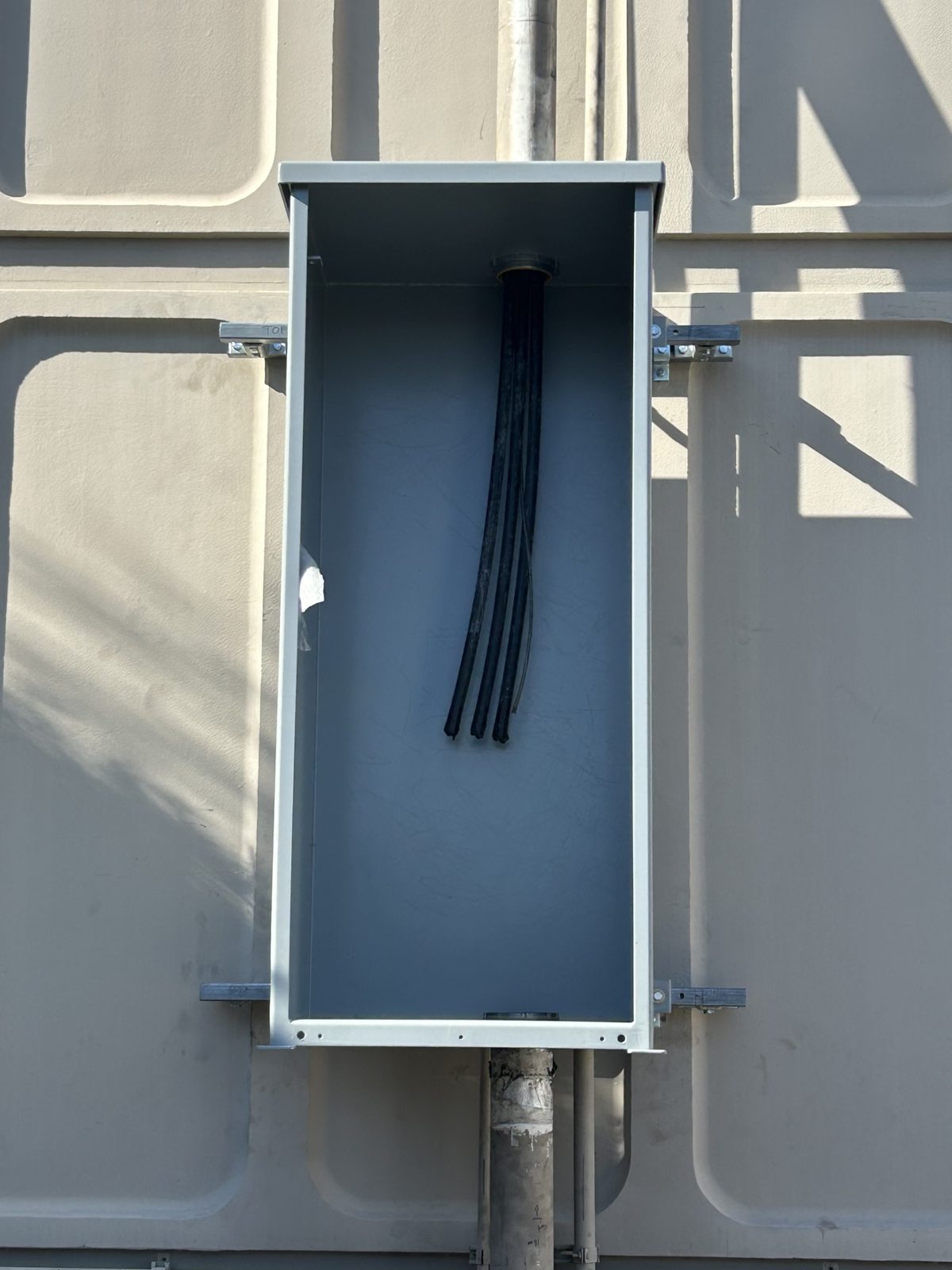 Wireway riser mid-install, with feeders pulled down from the overhead run and landed before dress-out.